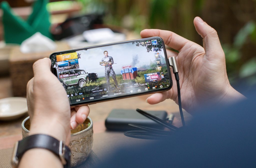 Person holding mobile phone playing Mobile Games that earned the highest mobile gaming revenue
